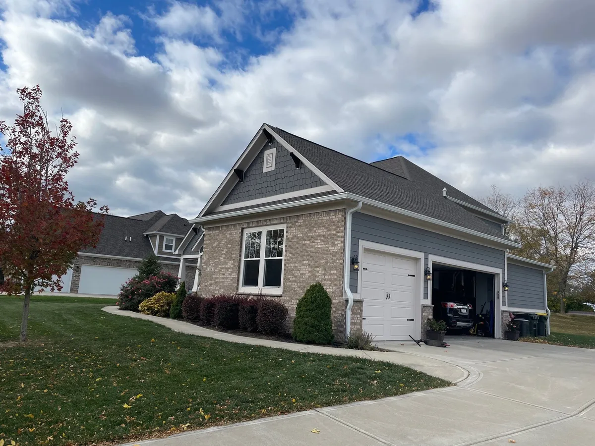 brick home with accent grey siding and dark asphalt roof