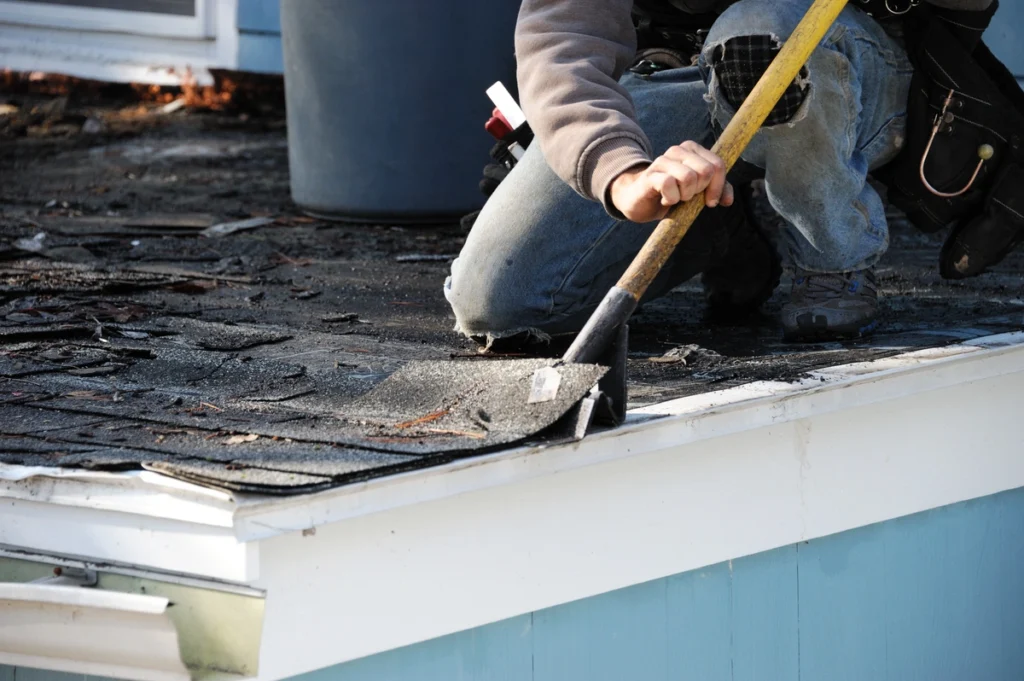 Closeup of roofer using shingle shovel to make repairs and complete roof maintenance