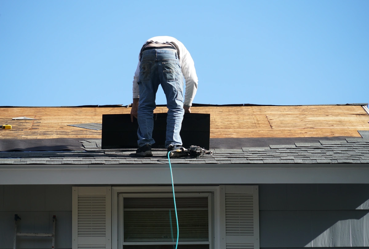 professional roofer installing new asphalt shingles on house roof