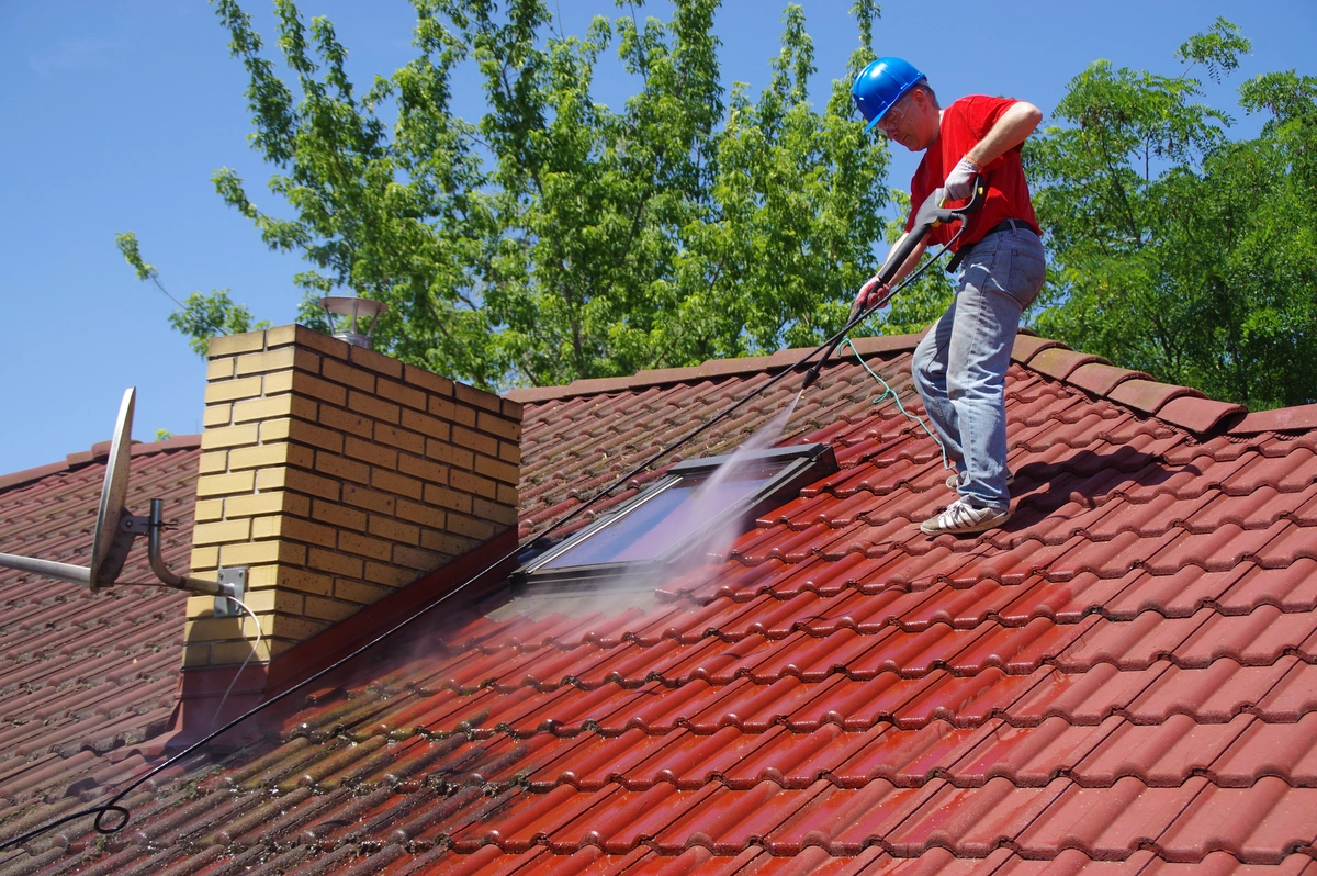 a roofer sprays down a tile roof