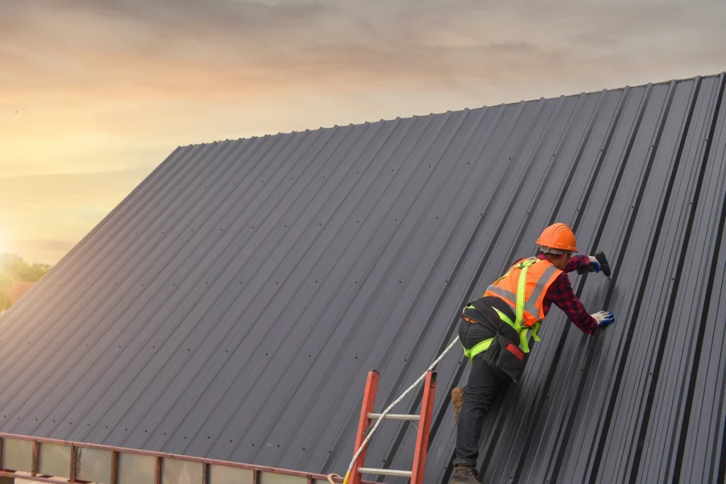 roofer on a metal roof, with a drill