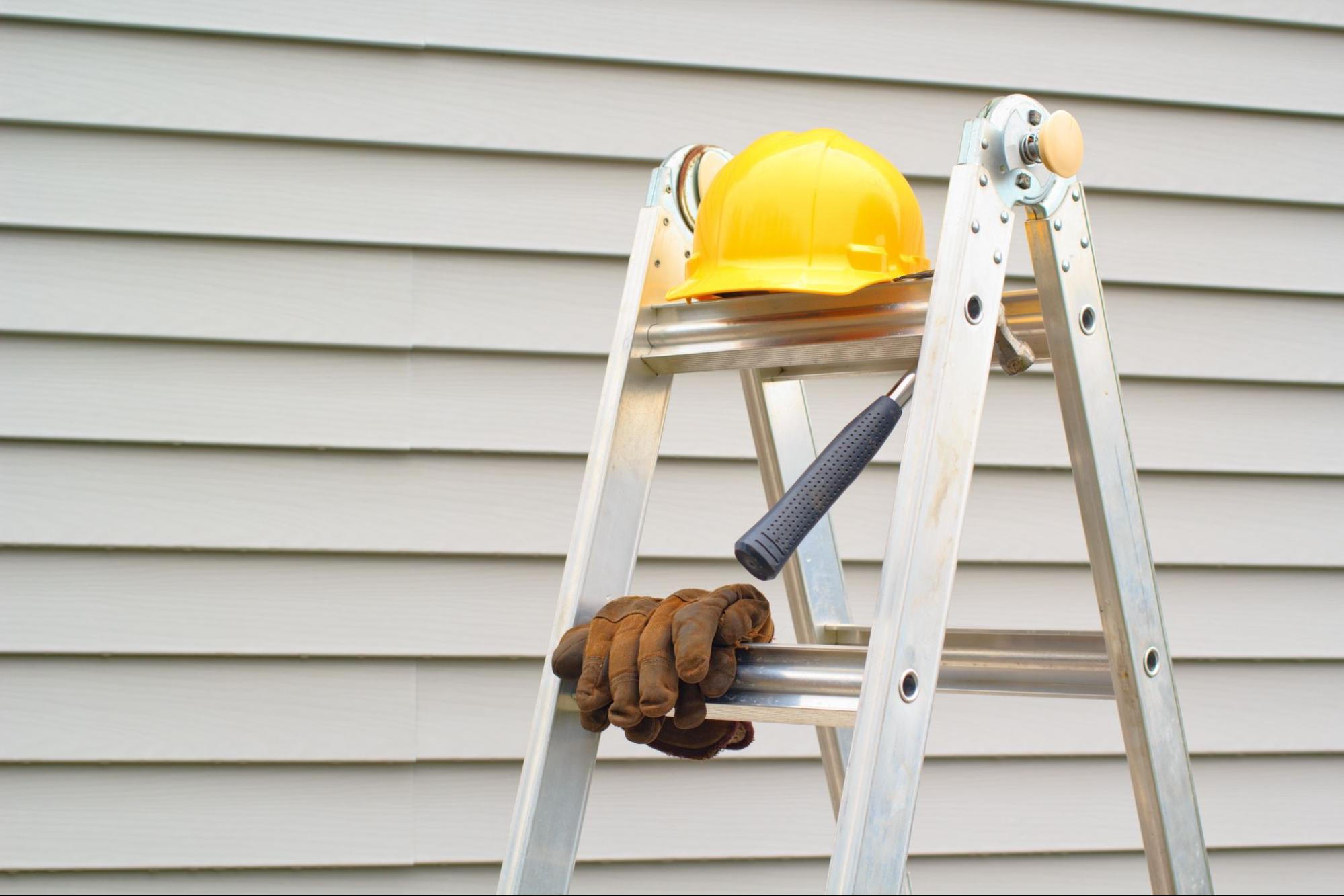 professional gear on ladder siding on background